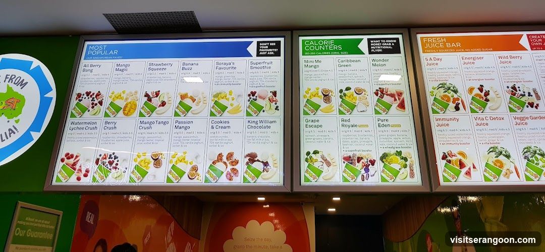 A brightly lit menu board displaying various smoothies and juices. The menu is divided into sections like 'Most Popular', 'Calorie Counters', and 'Fresh Juice Bar'. Each item includes a name, price, and a brief description of ingredients, along with an image of the product.