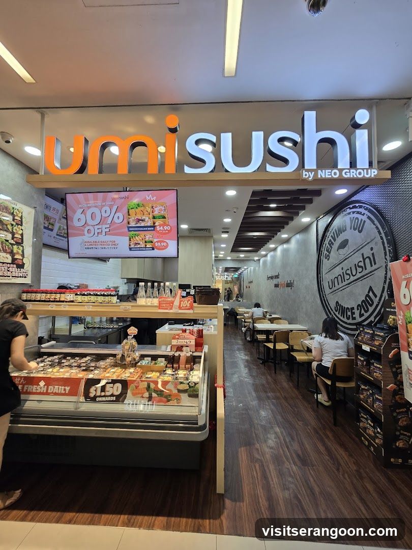 A brightly lit storefront for 'umi sushi by NEO GROUP'. The entrance features a large illuminated sign with orange and white lettering. Below the sign, a digital screen advertises a 60% OFF promotion. A refrigerated display case showcases sushi rolls with visible price tags, including '$1.50'. To the right, a circular wall graphic reads 'Serving you umisushi since 2001'. The interior shows a dining area with tables and chairs.