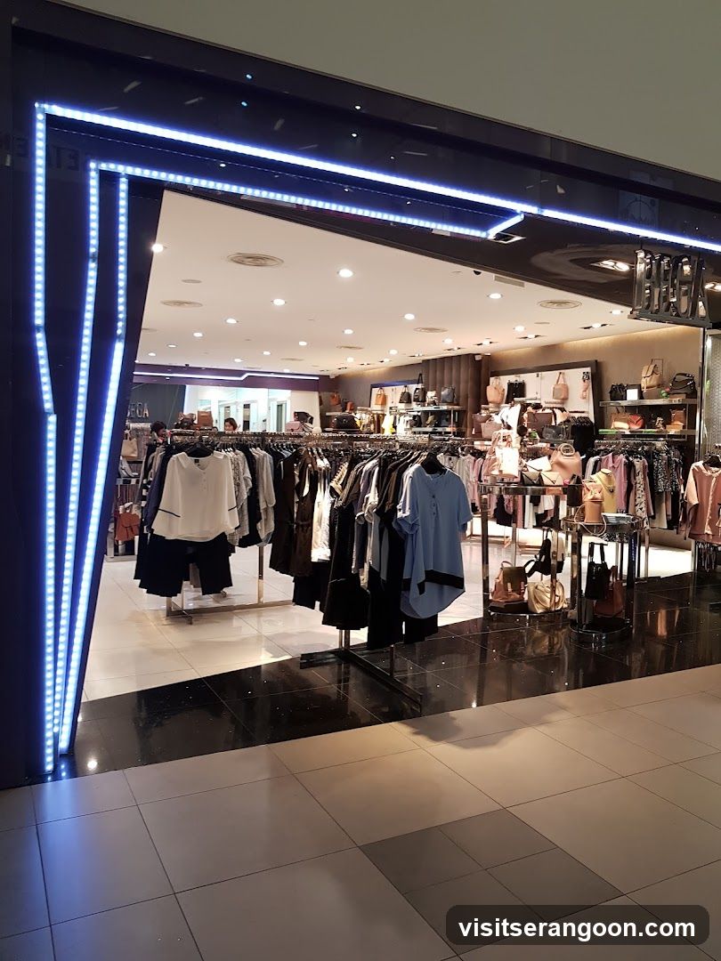 A brightly lit storefront entrance framed by vertical and horizontal blue LED strip lights. The interior displays racks of clothing, including shirts and pants, alongside shelves of handbags and accessories. The store number 13 is visible on the exterior wall.