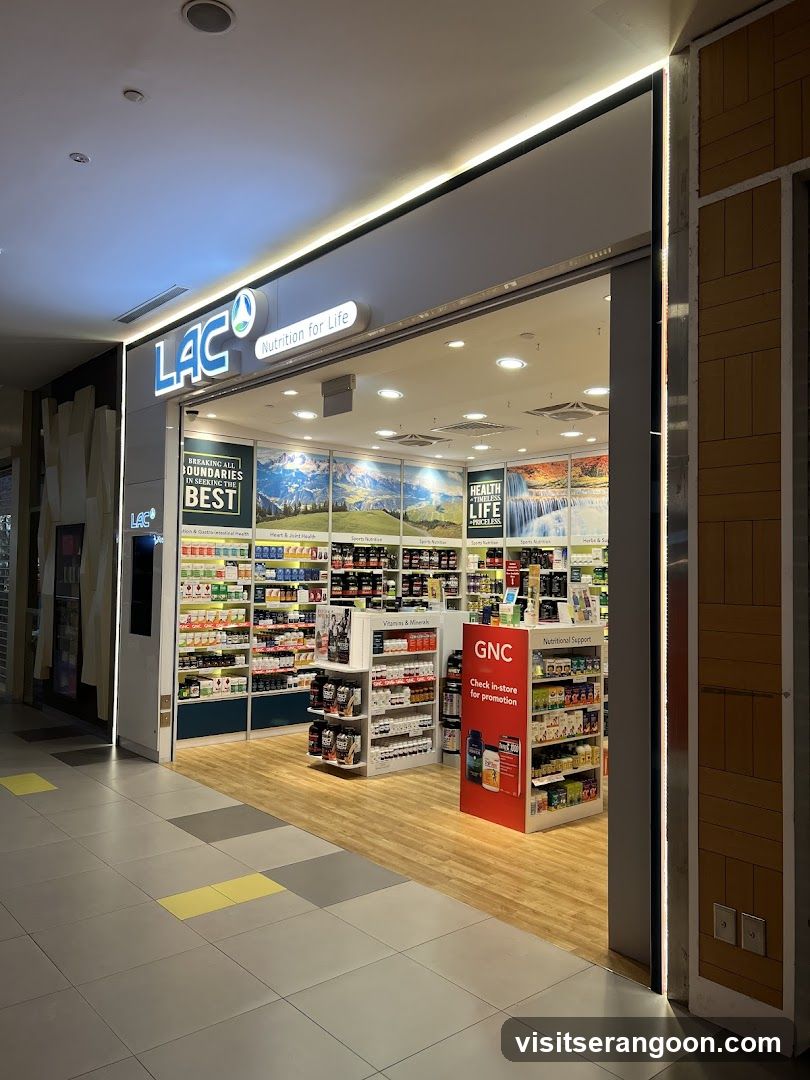 A brightly lit retail storefront with a large open entrance. The sign above reads 'LAC Nutrition For Life' in blue and white lettering. Inside, shelves are stocked with various health products, and a red GNC promotional stand is visible near the entrance. The floor inside is light wood, while the mall corridor outside has grey and yellow tiles.
