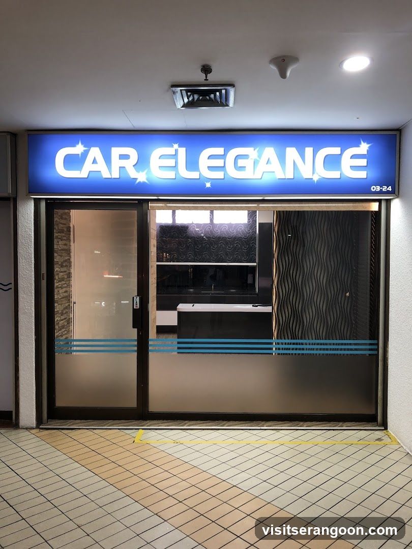 A brightly lit storefront with a large blue sign reading 'CAR ELEGANCE' in white letters. The entrance features glass doors and windows with blue horizontal stripes. A yellow line marks the floor in front of the store.