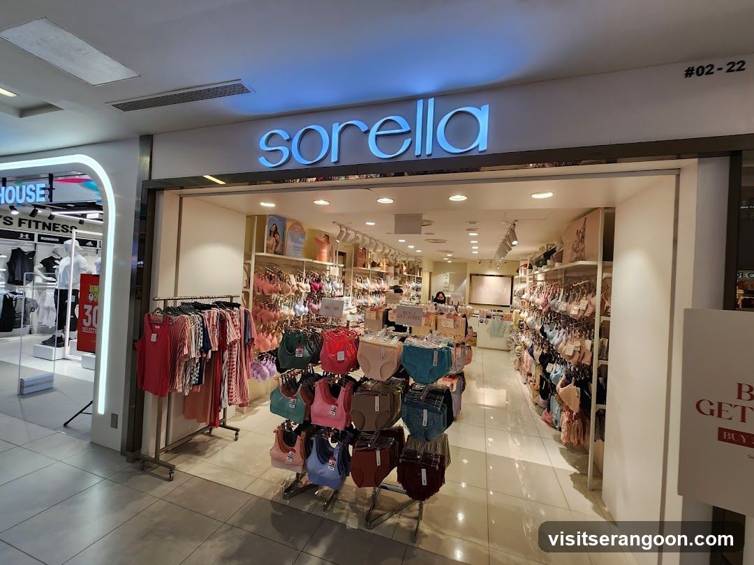 A brightly lit retail store entrance with a large, illuminated blue sign reading 'sorella' above the doorway. The store number '#02-22' is visible in the top right corner. Inside, racks of colorful clothing, including bras and tank tops, are displayed on metal stands. A promotional sign advertising 'UP TO 30% OFF' is visible on the left, and another sign partially visible on the right reads 'BUY 2 GET 1'.