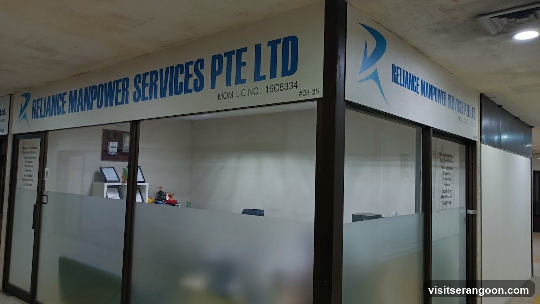 A storefront view of an office unit for Reliance Manpower Services Pte Ltd. The business name and logo are displayed on a large white sign above the glass entrance. The sign also includes the text 'MOM LIC NO: 16C8334' and the unit number '#03-35'. The office features glass doors and windows with frosted lower panels, through which some interior furniture and equipment are faintly visible.