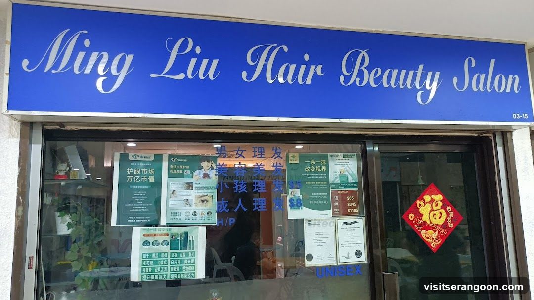A blue storefront sign with white cursive text reading 'Ming Liu Hair Beauty Salon' and unit number '03-15'. Below the sign, a glass window displays various posters, including a green advertisement for hair products, a service menu with Chinese characters, and a red diamond-shaped 'Fu' decoration. A 'UNISEX' sticker is visible on the lower glass.