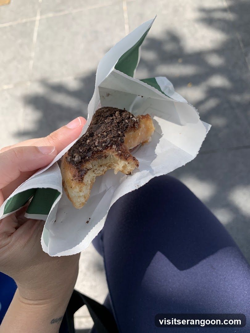 Hand holding a pastry in paper wrapper