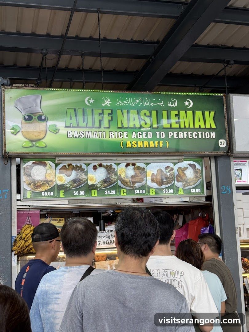 A food stall with a green sign displaying the name "ALIFF NASI LEMAK" and images of different nasi lemak sets with prices. Below the sign, a queue of people are waiting to order.