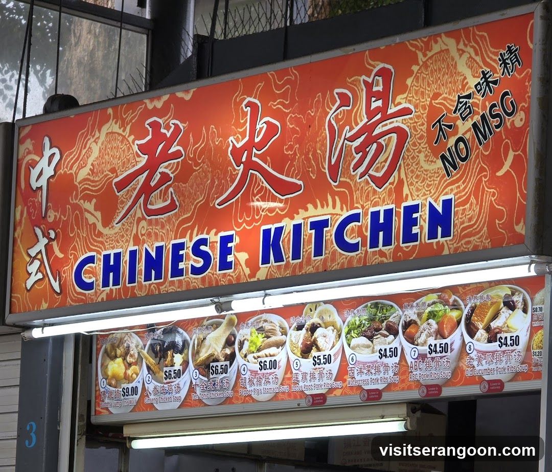 A brightly lit sign for "CHINESE KITCHEN" with Chinese characters above. The sign features a red background with a dragon motif and the text "NO MSG". Below the main sign, a menu displays various soup dishes with images and prices.