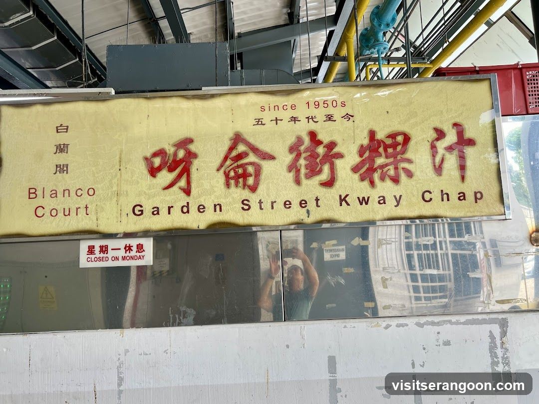 A sign for Blanco Court Garden Street Kway Chap, indicating it has been in business since the 1950s. The sign also states that the establishment is closed on Mondays.