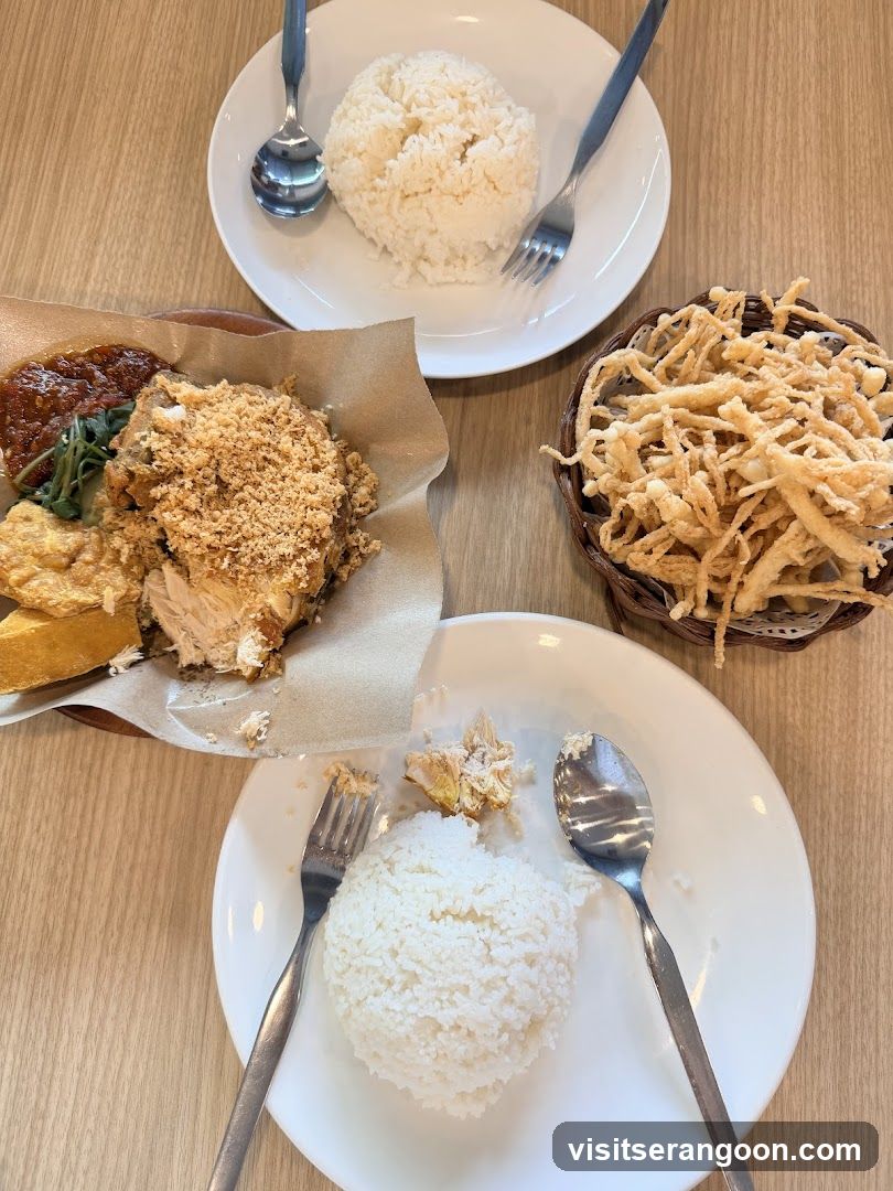 Two plates of rice with fried chicken and a basket of fried mushrooms