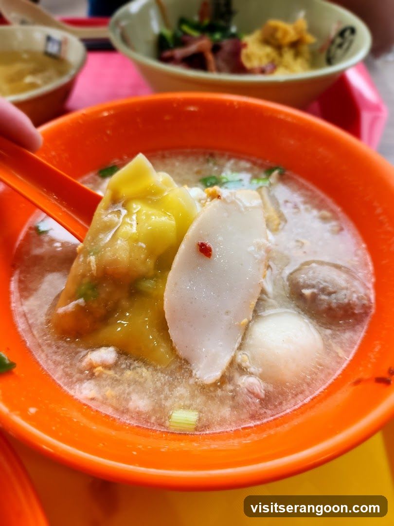 Close-up of a bowl of soup with dumplings and fish cakes