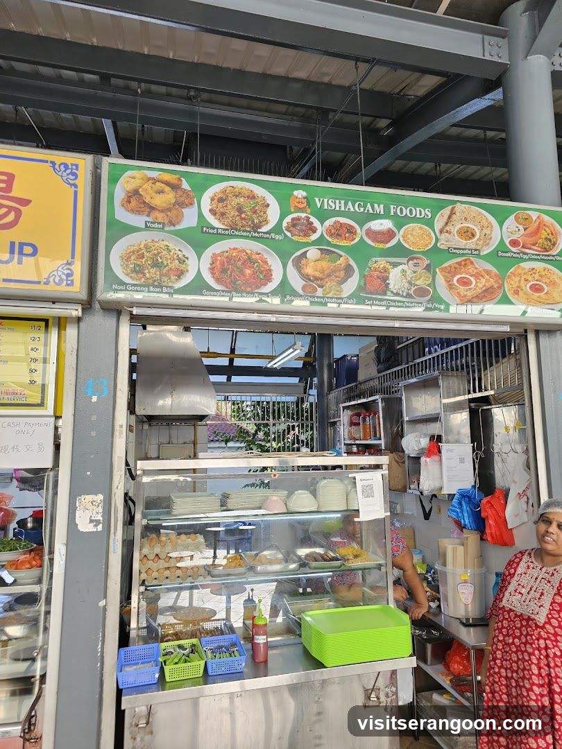 A food stall with a large menu board displaying various dishes. The stall has a display case with food items and a counter with condiments and utensils. A woman in a red dress is standing to the right.