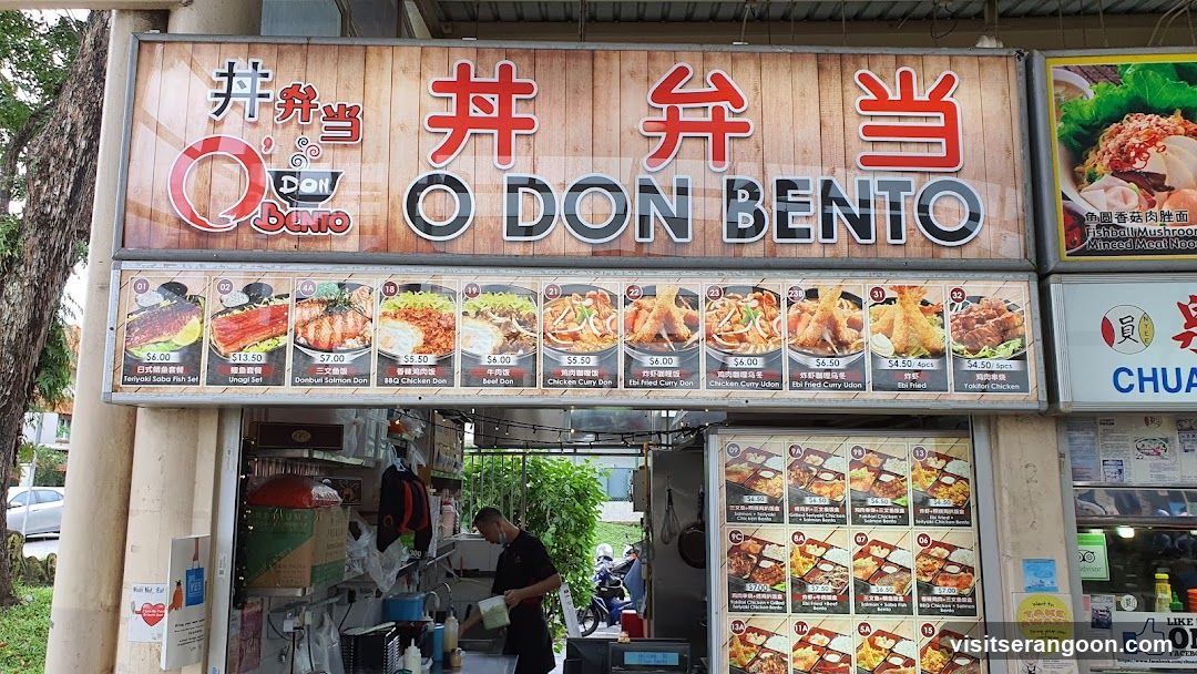 A storefront sign for O DON BENTO, a Japanese bento restaurant. The sign features the restaurant name in English and Japanese characters, along with images and prices of various bento boxes and dishes. Below the main sign, there are multiple rows of menu items displayed with pictures and descriptions. A man is visible working behind the counter.