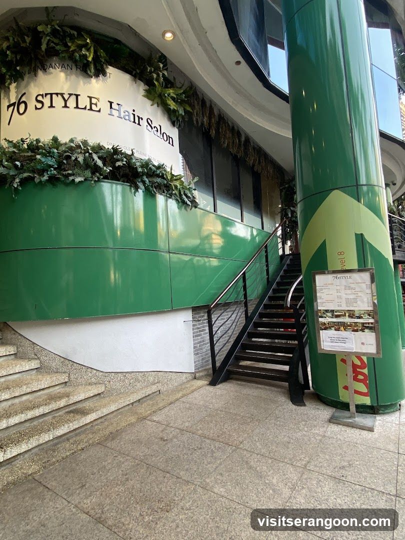 A menu board for 76STYLE Hair Salon is displayed on a stand next to a staircase.